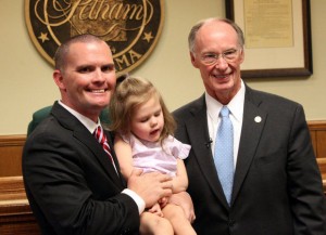 Dustin Chandler of the Birmingham area holds his 3-year-old daughter, Carly, next to Gov. Robert Bentley during a gathering at Pelham City Hall on July 22, 2014, in celebration of the passage of Carly's Law. Families with children who could benefit from the marijuana-derived oil to treat seizures also attended.
